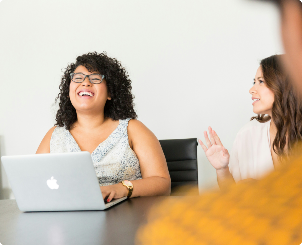 Two women looking at a laptop laughing