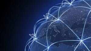 A digital rendering of Earth at night, showcasing glowing blue network lines connecting various regions across the globe, symbolizing global business expansion, international connectivity, and digital transformation.